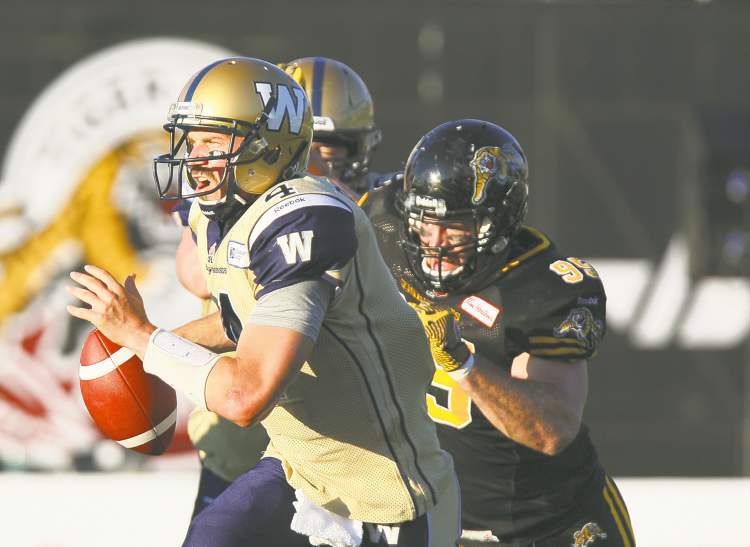CP
Aaron Lynett / the canadian press
Winnipeg quarterback Buck Pierce runs for his life Saturday night. In hot pursuit is Hamilton defender Brian Bulcke.