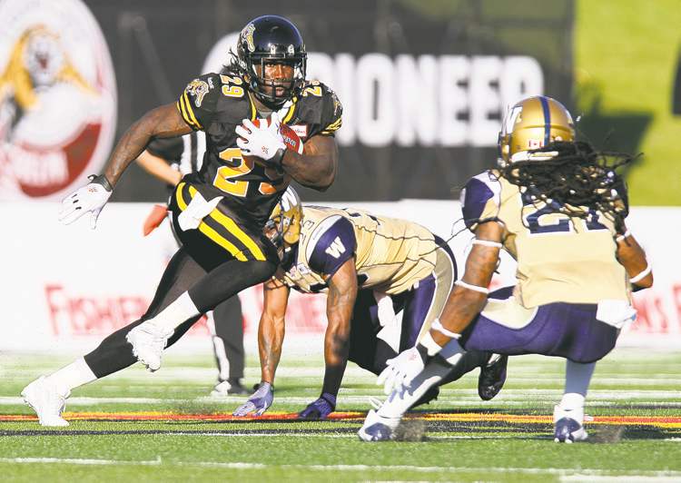 aaron lynett / the canadian press
Hamilton Tiger-Cats running back Chevon Walker hauls the pigskin as Winnipeg Blue Bombers' DB Marty Markett waits to pounce.