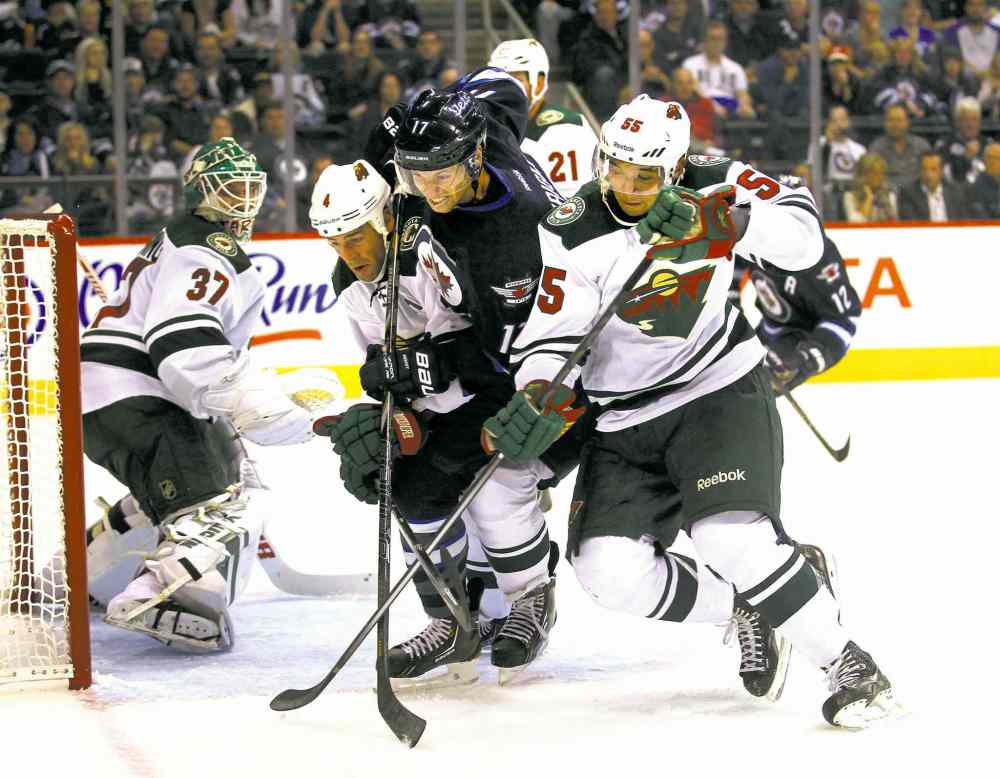 phil hossack / winnipeg free press
The Jets' James Wright is sandwiched by the Minnesota Wild's Clayton Stoner (left) and Erik Haula in front of the Wild net in second-period action Thursday.