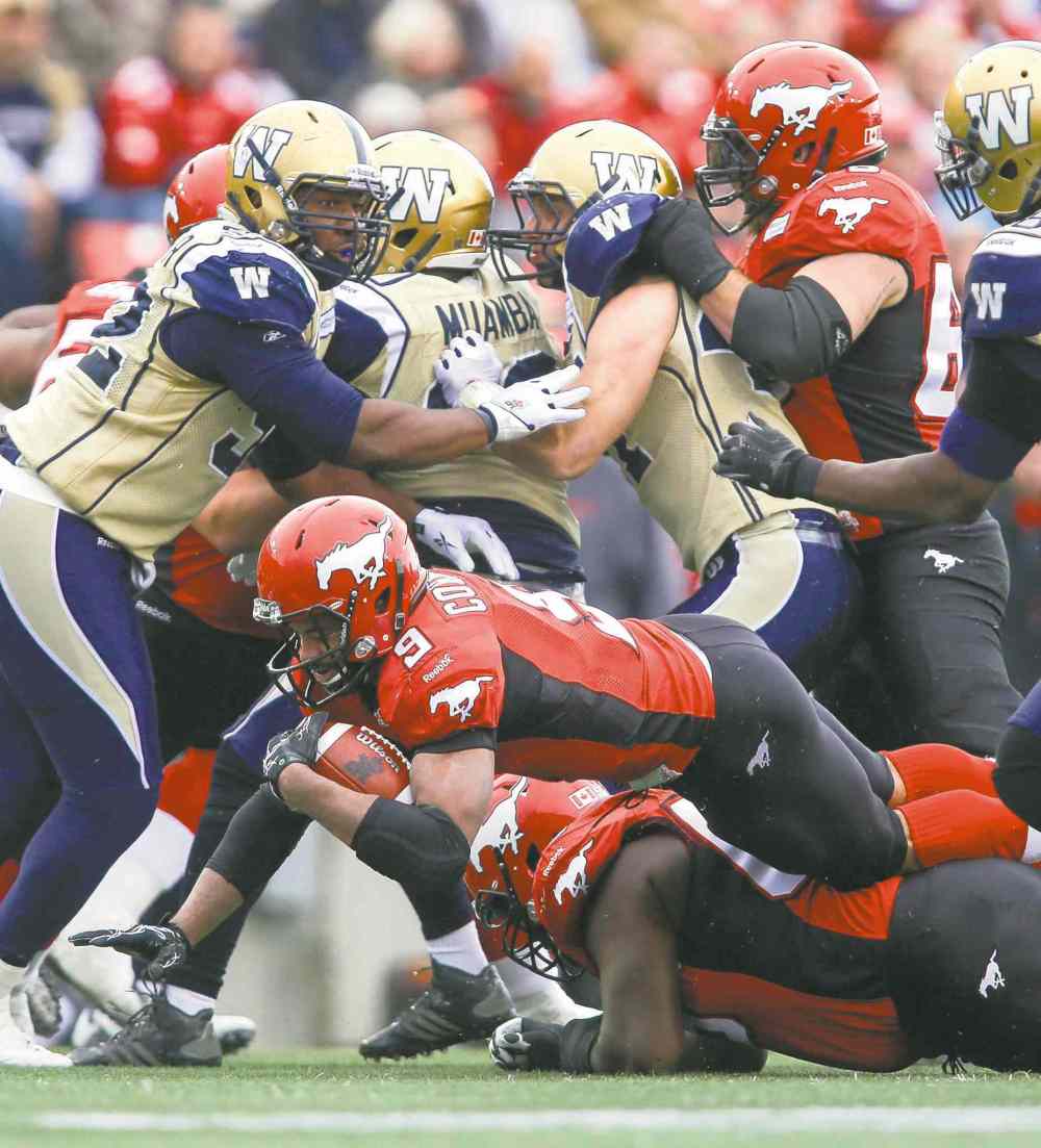 CP
Jeff McIntosh / the canadian press
Winnipeg�s Bryant Turner Jr. (left) and Alex Hall (right) look on as Calgary running back Jon Cornish (centre) dives for extra yardage.
