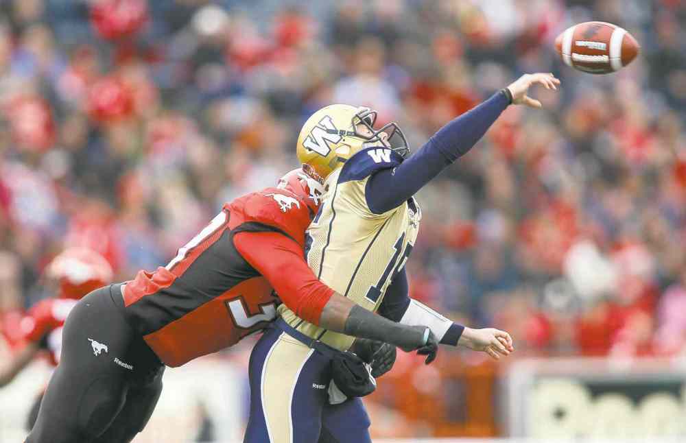 Jeff McIntosh / The Canadian Press
Blue Bombers' quarterback Max Hall takes a bone-rattling hit from Calgary Stampeders defensive lineman Charleston Hughes Saturday.