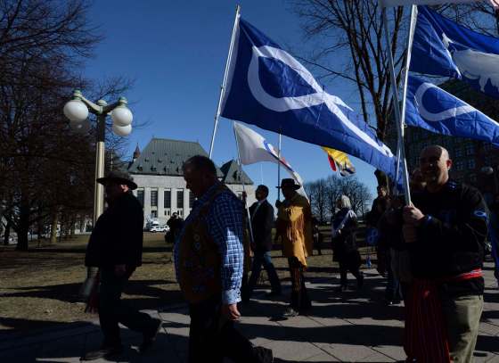 Sean Kilpatrick / The Canadian PressDavid Chartrand, president of the Manitoba Metis Federation, middle, carries the Metis flag as he and fellow Metis Federation leaders and delagates march to the Supreme Court of Canada in Ottawa on Thursday.