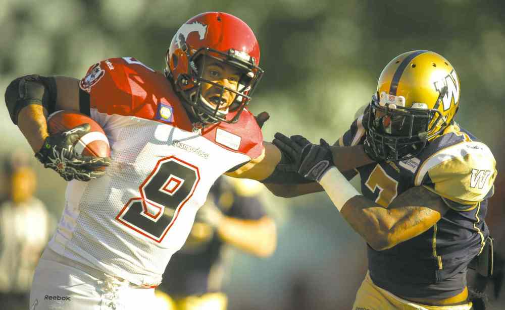 Jeff Mcintosh / The Canadian Press
Stampeders' running back Jon Cornish ran roughshod over the Bombers defence Saturday, including this straight-arm escape of Demond Washington.
