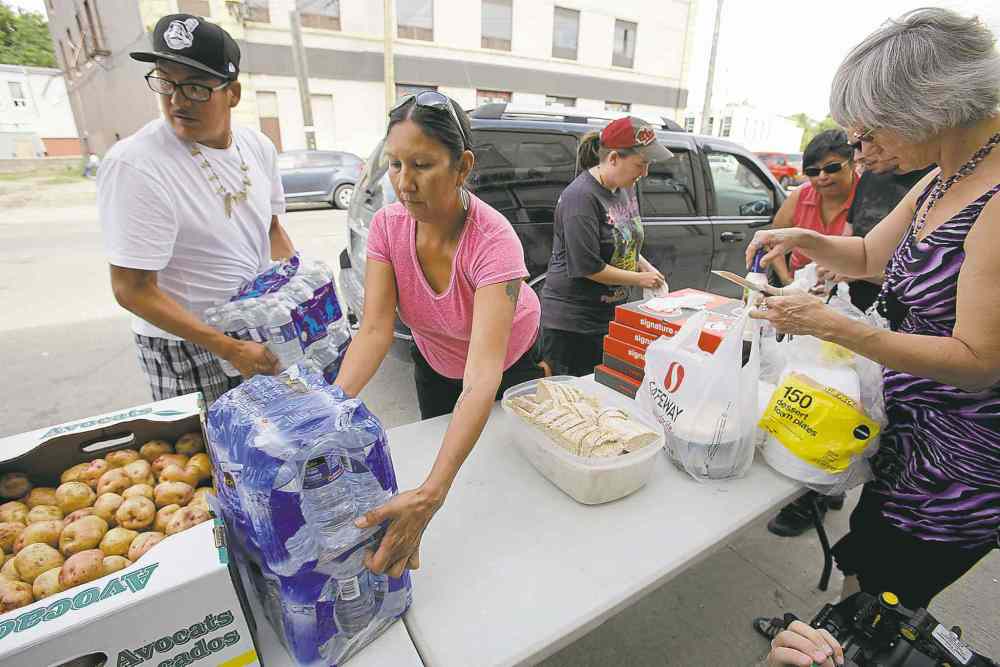 Winnipeg Free Press
john woods / winnipeg free press
Althea Guiboche (centre) and volunteers distribute food and clothing Sunday. Guiboche had invited Gord Steeves and his wife, Lorrie (below), to volunteer.