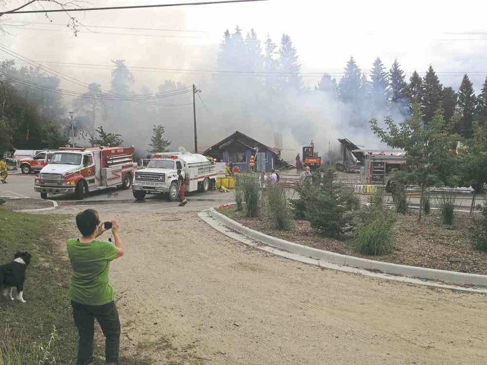 Jason Bell / Winnipeg Free Press
A passerby takes pictures as emergency personnel work to extinguish the fire at the West Hawk Inn Friday morning.
