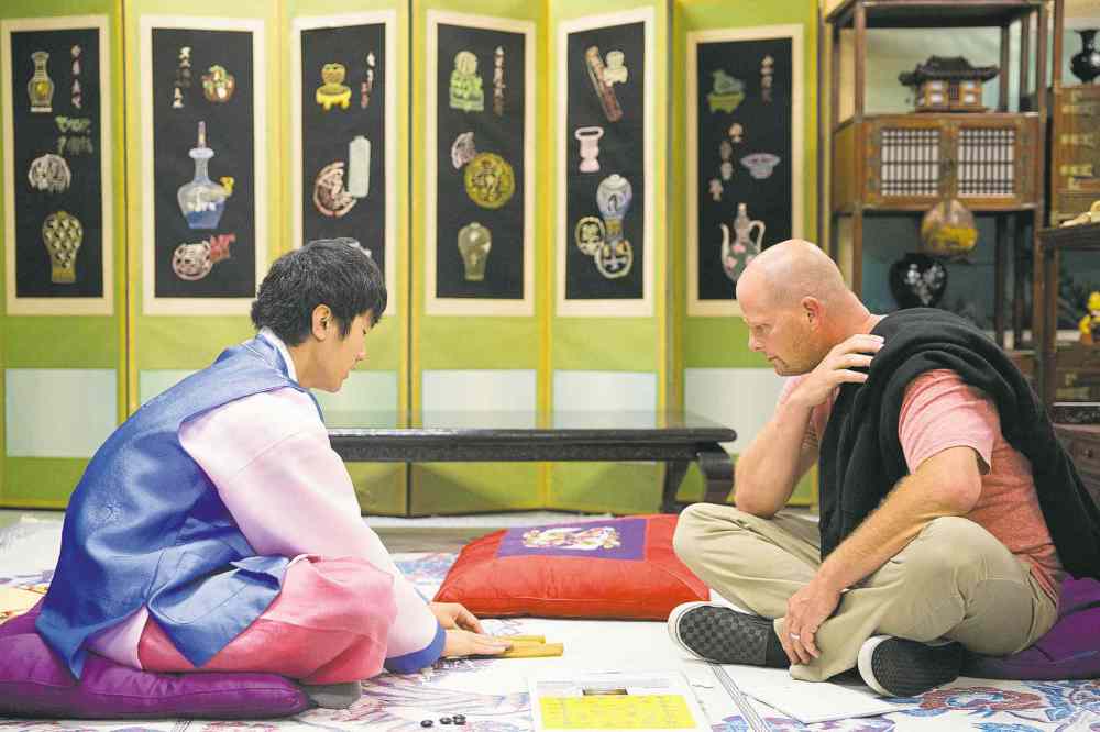 Mikaela MacKenzie / Winnipeg Free Press
Young-Ok Kang-Bohr (left) teaches Sheldon Brandt to play a traditional game at the Korean pavilion of Folklorama in Winnipeg Wednesday.