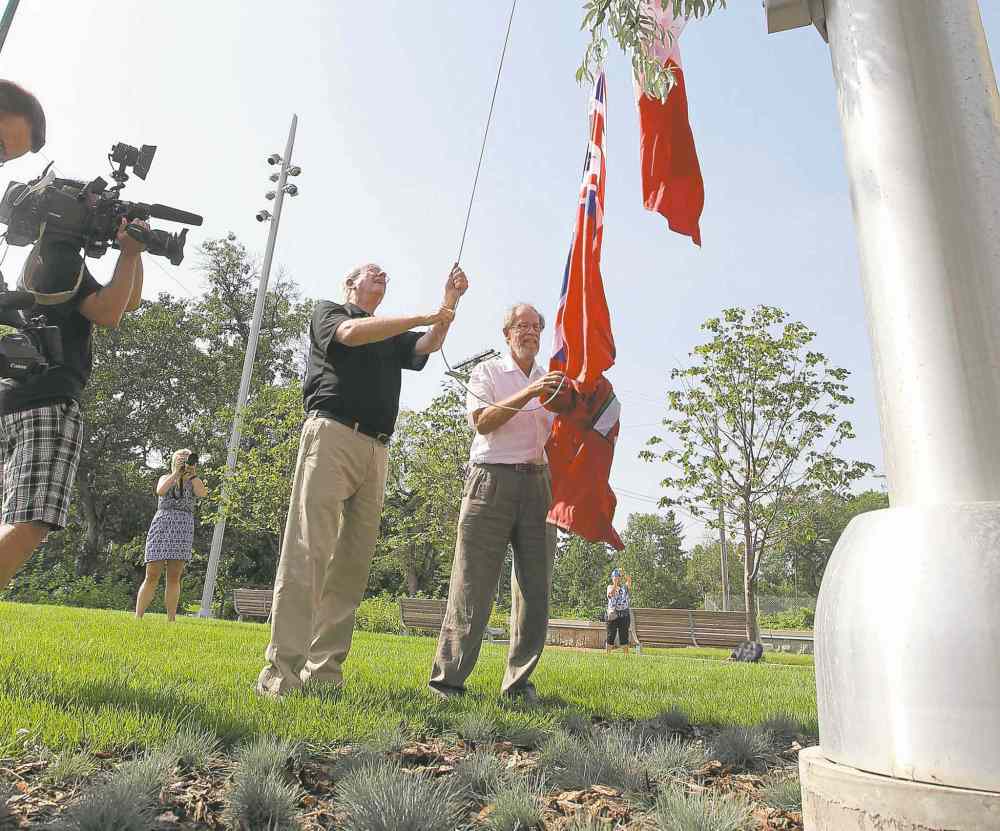 Jerry Gray (black shirt) and Garry Hilderman both with Friends of Upper Fort Garry, cut the ribbon and raise flags at the official unveiling of Upper Fort Garry at the new provincial park on Main street Friday. Aug 14, 2015 Ruth Bonneville / Winnipeg Free Press