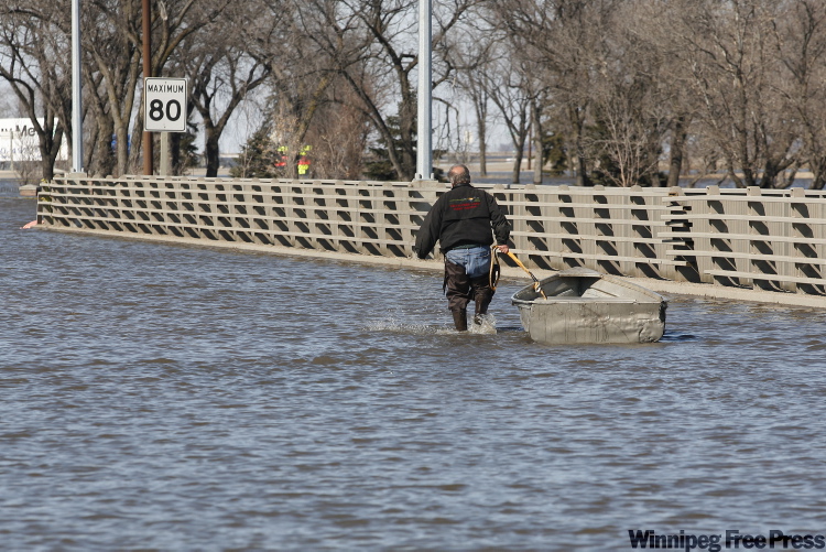 JOHN WOODS / THE CANADIAN PRESS ARCHIVES
A resident of Morris pulls a boat down Highway 75 across the Morris River bridge to his business, which was left isolated by flood water, during last spring’s flooding.