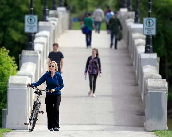 PHIL HOSSACK / WINNIPEG FREE PRESSSylvie Roy, walking her bike across the Assiniboine Park pedestrian bridge, says helmets are a good idea but she hasn't found one she likes.