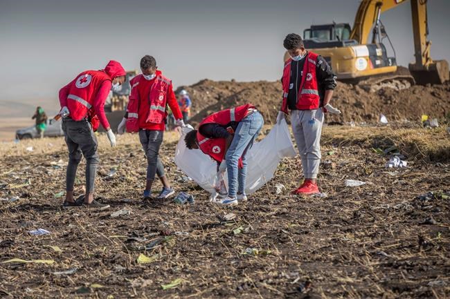 Rescue workers at Bishoftu, or Debre Zeit, outside Addis Ababa, Ethiopia, Monday, March 11, 2019, where Ethiopia Airlines Flight 302 crashed Sunday. Investigators are trying to determine the cause of a deadly crash Sunday involving a new aircraft model touted for its environmentally friendly engine that is used by many airlines worldwide. (AP Photo/Mulugeta Ayene)