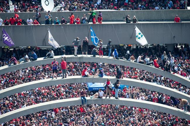 Fans climb the arches at Nathan Phillips Square ahead of the 2019 Toronto Raptors Championship parade in Toronto, on Monday, June 17, 2019. THE CANADIAN PRESS/Andrew Lahodynskyj