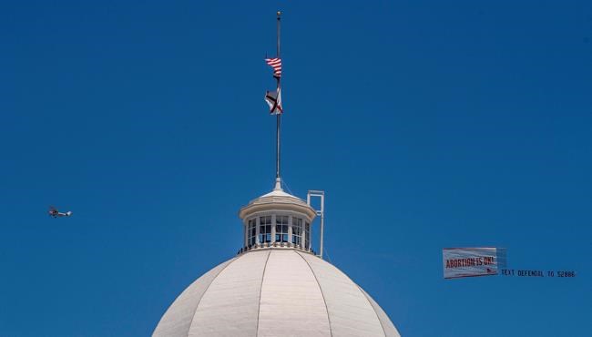 Legal abortion supporters fly a banner reading Abortion is OK over the Alabama State Capitol building in downtown Montgomery, Ala., on Wednesday May 15, 2019. Alabama HB314, the near-total ban on abortion bill, passed the Alabama legislature on Tuesday. (Mickey Welsh/The Montgomery Advertiser via AP)
