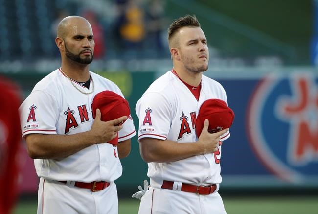 Los Angeles Angels' Albert Pujols, left, and Mike Trout listen to the national anthem before the team's baseball game against the Oakland Athletics on Friday, June 28, 2019, in Anaheim, Calif. (AP Photo/Marcio Jose Sanchez)