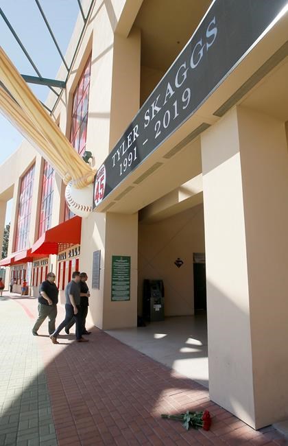 Employees walk past a sign for pitcher Tyler Skaggs at Angel Stadium in Anaheim, Calif., Monday, July 1, 2019. Skaggs died at the age of 27, stunning Major League Baseball and leading to the postponement of the team's game against the Texas Rangers on Monday. (AP Photo/Alex Gallardo)