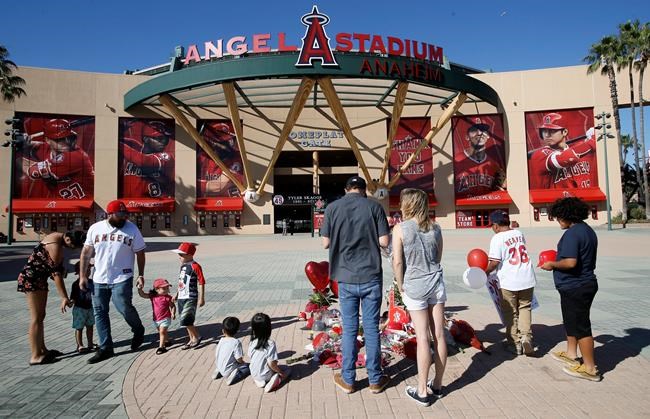 Los Angeles Angel mourners stand at a memorial to give their condolences for pitcher Tyler Skaggs at Angel Stadium in Anaheim, Calif., Monday, July 1, 2019. Skaggs died at the age of 27, stunning Major League Baseball and leading to the postponement of the team's game against the Texas Rangers on Monday. (AP Photo/Alex Gallardo)