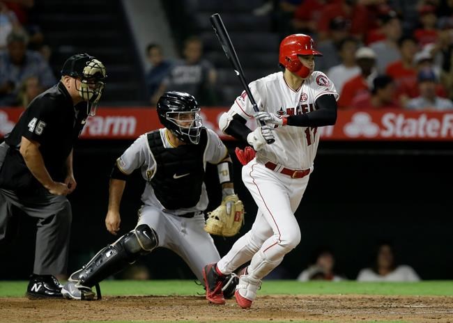 Los Angeles Angels designated hitter Shohei Ohtani, right, hits a ground out to second, with Pittsburgh Pirates catcher Jacob Stallings, center, and umpire Jeff Nelson, left, watching during the third inning of a baseball game in Anaheim, Calif., Monday, Aug. 12, 2019. (AP Photo/Alex Gallardo)