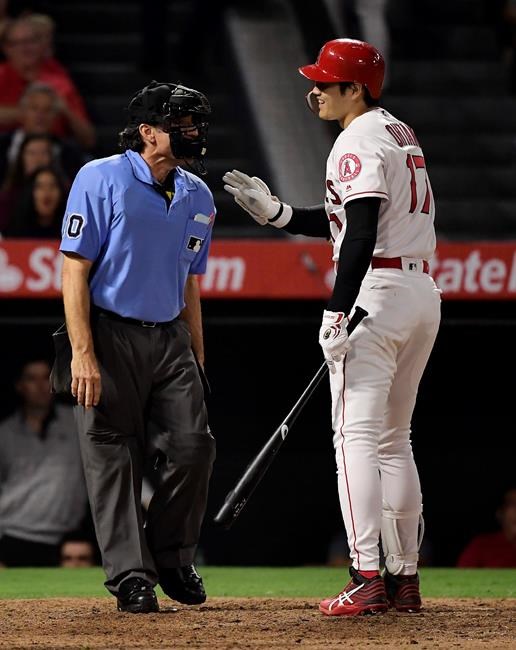 Los Angeles Angels' Shohei Ohtani, of Japan, talks with home plate umpire Phil Cuzzi after striking out during the sixth inning of the team's baseball game against the Oakland Athletics on Thursday, June 27, 2019, in Anaheim, Calif. (AP Photo/Mark J. Terrill)