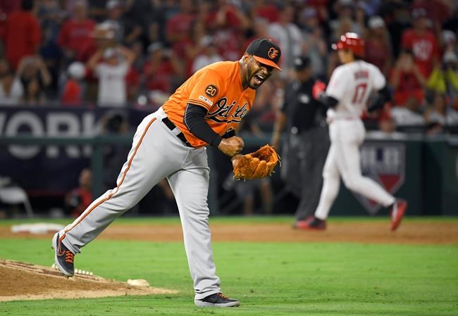 Baltimore Orioles relief pitcher Mychal Givens, left, celebrates after the Orioles defeated the Los Angeles Angels 8-7 as Shohei Ohtani, of Japan, heads to third in a baseball game Saturday, July 27, 2019, in Anaheim, Calif. (AP Photo/Mark J. Terrill)