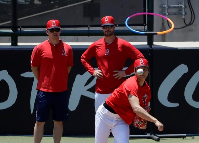 Los Angeles Angels' Shohei Ohtani, right, throws as pitching coach Doug White on in the bullpen before a baseball game against the Cincinnati Reds in Anaheim, Calif., Wednesday, June 26, 2019. Ohtani threw off a mound for the first time since Tommy John surgery Oct 1, 2018. (AP Photo/Chris Carlson)
