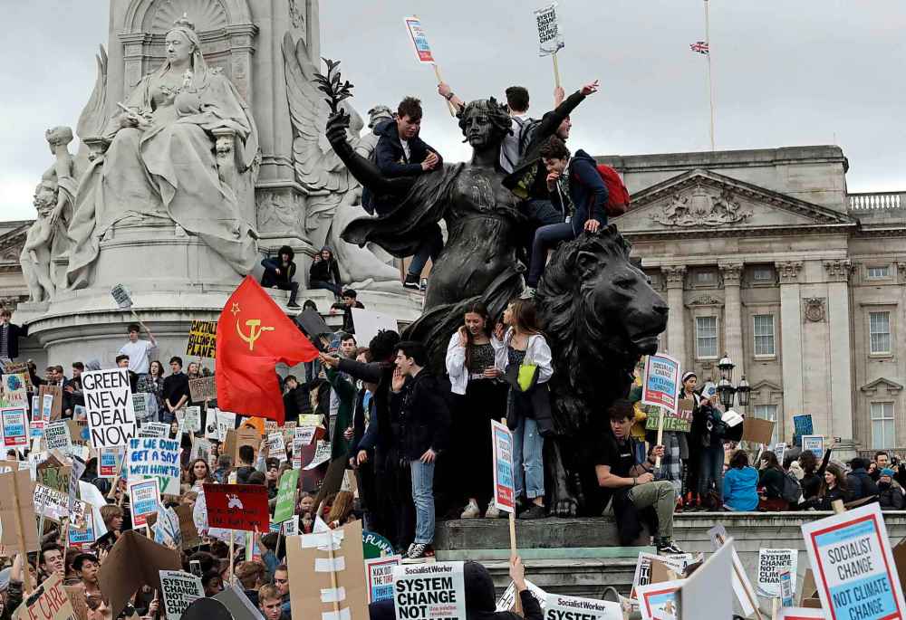 Youngsters stand on the Queen Victoria Memorial outside Buckingham Palace as they take part in a worldwide student climate protest in London, England on March 15 (Matt Dunham / The Associated Press files)