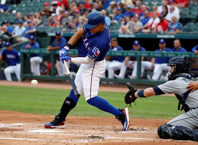 Texas Rangers' Shin-Soo Choo, left, connects for a single that he stretched into a double in the first inning of a baseball game as Seattle Mariners' Tom Murphy looks on in Arlington, Texas, Monday, May 20, 2019. (AP Photo/Tony Gutierrez)