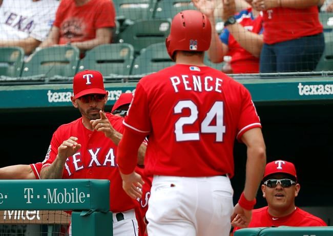 Texas Rangers manager Chris Woodward, left, points to Hunter Pence (24) after Pence scored on a double by Nomar Mazara in the first inning of a baseball game against the Seattle Mariners in Arlington, Texas, Wednesday, May 22, 2019. (AP Photo/Tony Gutierrez)