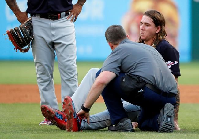 A member of the Cleveland Indians staff checks on starting pitcher Mike Clevinger, right, who fell off the mound while delivering a pitch to the Texas Rangers in the second inning of baseball game in Arlington, Texas, Monday, June 17, 2019. Clevinger continued playing in the game. (AP Photo/Tony Gutierrez)
