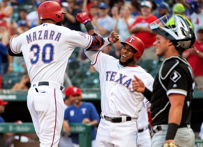 Texas Rangers' Nomar Mazara (30) is congratulated by Elvis Andrus, center, after hitting a two-run home run that scored Andrus off of Chicago White Sox starting pitcher Reynaldo Lopez during the first inning of a baseball game Friday, June 21, 2019, in Arlington, Texas. White Sox catcher James McCann is at right. (AP Photo/Jeffrey McWhorter)