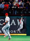 Los Angeles Angels second baseman Tommy La Stella watches as the ball glances off the glove of right fielder Kole Calhoun and falls behind the wall for a two-run home run by Texas Rangers' Asdrubal Cabrera diromg the fourth inning of a baseball game in Arlington, Texas, Tuesday, April 16, 2019. (AP Photo/Tony Gutierrez)