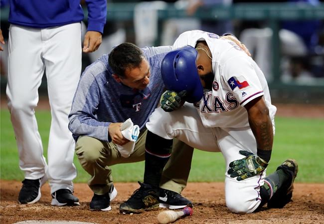 A member of the staff, center, and manager Chris Woodward, left, check on Texas Rangers' Danny Santana, right, who was hit by a pitch from St. Louis Cardinals relief pitcher Carlos Martinez in the ninth inning of a baseball game in Arlington, Texas, Saturday, May 18, 2019. Santana left the game with an unknown injury. (AP Photo/Tony Gutierrez)