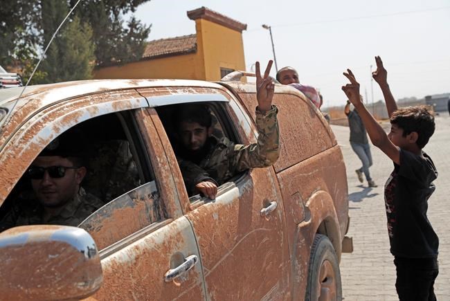 Members of Turkey-backed Syrian National Army (former FSA) flash the V-sign as they drive back to Turkey after they went in for some time on inspection according to the Turkish police entourage in the same area at the border between Turkey and Syria, in Akcakale, Sanliurfa province, southeastern Turkey, Wednesday, Oct. 9, 2019. Turkish President Recep Tayyip Erdogan has long threatened to send troops into northeastern Syria to clear the border region of Syrian Kurdish fighters whom Turkey considers a serious security threat. (AP Photo/Lefteris Pitarakis)