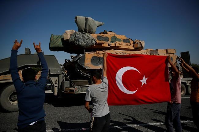 Local residents applaud as a convoy of Turkish forces trucks transporting tanks is driven in Sanliurfa province, southeastern Turkey, at the border with Syria, Saturday, Oct. 12, 2019. Turkey says its military offensive has taken central Ras al-Ayn, a key border town in northeastern Syria, and its most significant gain since its cross-border operation began against Syrian Kurdish fighters began. (AP Photo/Lefteris Pitarakis)