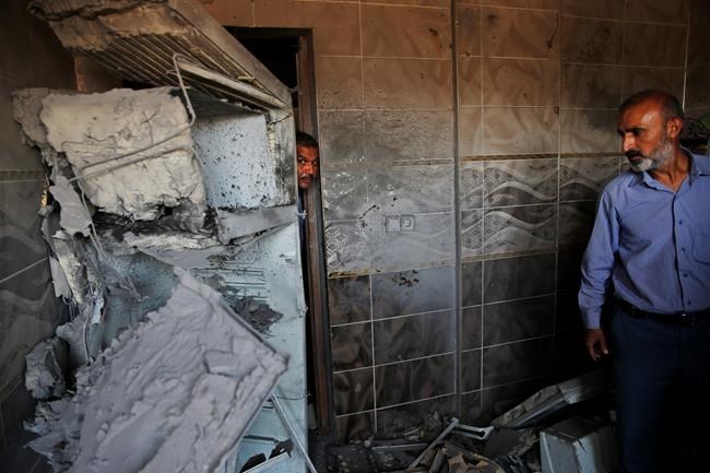 Halil Tokak, right, the neighborhood chief and another resident, inspect the damage on a house, caused by a mortar fired from inside Syria, on the Turkish town of Akcakale, southeastern Turkey, Saturday, Oct. 12, 2019. Nobody got hurt by the attack as the owners of the house were not at home at the time of the attack. (AP Photo/Lefteris Pitarakis)