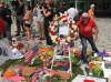 A woman places an object on the back of a red and white wreath with a statement from Prime Minister Justin Trudeau at a memorial for victims of the Orlando massacre in Orlando, Fla. Thursday, June 16, 2016. THE CANADIAN PRESS/Alex Panetta