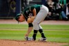 Oakland Athletics starting pitcher Daniel Mengden cleans mud off his shoes as he throws during the first inning of a spring training baseball game against the Seattle Mariners, Friday, Feb. 22, 2019, in Peoria, Ariz. (AP Photo/Charlie Riedel)
