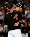 Arizona Diamondbacks' Carson Kelly scores on a double hit by Zach Greinke as Milwaukee Brewers catcher Yasmani Grandal looks down during the fifth inning of a baseball game, Saturday, July 20, 2019, in Phoenix. (AP Photo/Matt York)