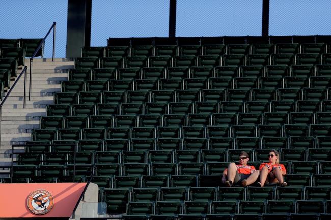 Spectators sit in almost empty section as they watch the first inning of a baseball game between the Baltimore Orioles and the Toronto Blue Jays, Thursday, Aug. 1, 2019, in Baltimore. (AP Photo/Julio Cortez)