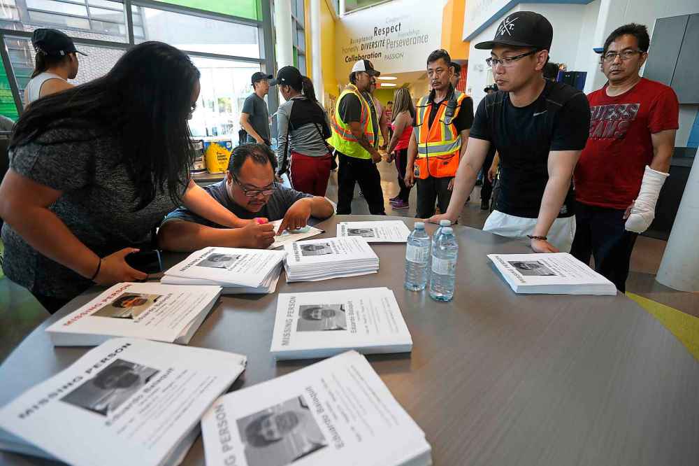 JOHN WOODS / WINNIPEG FREE PRESS FILES
Edward Balaquit, right and other volunteers plan their search for Edward's missing father in Winnipeg in June.