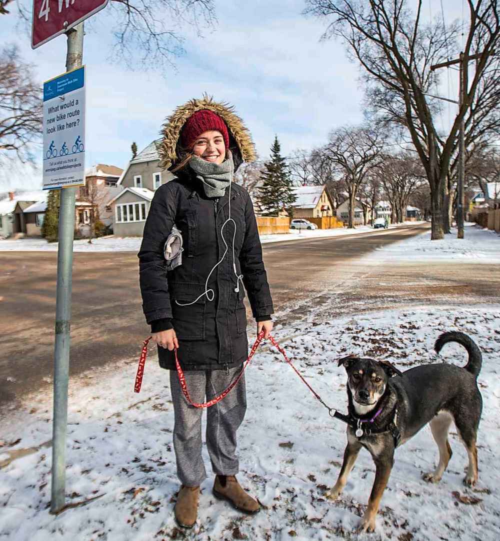 MIKAELA MACKENZIE / WINNIPEG FREE PRESS
Elena Howard-Scott walks her dog along Wolseley Avenue in Winnipeg on Monday near a sign asking for residents' input on a bike lane along Wolseley Avenue in Winnipeg on Monday.