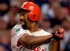 FILE - In this Aug. 4, 2004, file photo, Philadelphia Phillies' Doug Glanville follows through on an RBI triple hit off San Diego Padres pitcher Adam Eaton during the third inning in San Diego. The Chicago Cubs say they're investigating a fan using what appeared to be an offensive hand gesture associated with racism behind Glanville, now a television reporter, who was on the air for NBC Sports Chicago. (AP Photo/Denis Poroy, File)