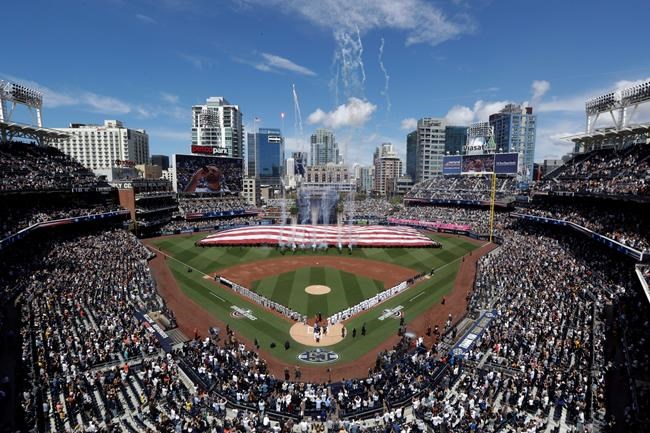 Players for the San Francisco Giants and the San Diego Padres stand during the singing of the national anthem before an opening day baseball game, Thursday, March 28, 2019, in San Diego. (AP Photo/Gregory Bull)