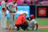 Philadelphia Phillies' Andrew McCutchen, right, is helped by a trainer after being injured while trying to get back to first base during the first inning of a baseball game against the San Diego Padres, Monday, June 3, 2019, in San Diego. Phillies manager Gabe Kapler, left, watches alongside first base coach Paco Figueroa. (AP Photo/Gregory Bull)