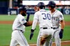 San Diego Padres' Manuel Margot, left, celebrates with Eric Hosmer (30) and Hunter Renfroe, right, after all three scored on a double by Luis Urias during the first inning of the team's baseball game against the Tampa Bay Rays on Tuesday, Aug. 13, 2019, in San Diego. (AP Photo/Gregory Bull)