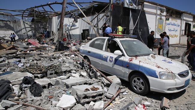 Debris covers the ground and an emergency vehicle after an airstrike at a detention center in Tajoura, east of Tripoli in Libya, Wednesday, July 3, 2019. An airstrike hit the detention center for migrants early Wednesday, killing several. (AP Photo/Hazem Ahmed)