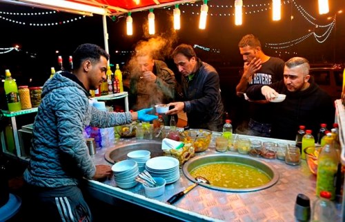 ADVANCE FOR PUBLICATION ON MONDAY, MAR. 11, AND THEREAFTER - In this Wednesday, Feb. 13, 2019 photo, a chickpeas vendor serves customers in Tahrir Square in Baghdad, Iraq. For the first time in 15 years, Iraq is not at war. The defeat of the Islamic State group after a ruinous four-year war has given the population a moment of respite, and across the capital Baghdad there is a guarded sense of hope. The city's infamous blast walls are coming down, restaurants, amusement parks and malls are brimming with families and shoppers who don't have to worry where the next car bomb will explode. But massive hurdles lie ahead, and many worry the calm is only temporary before a slide back into the violence that has dominated Iraq for the past four decades. (AP Photo/Khalid Mohammed)