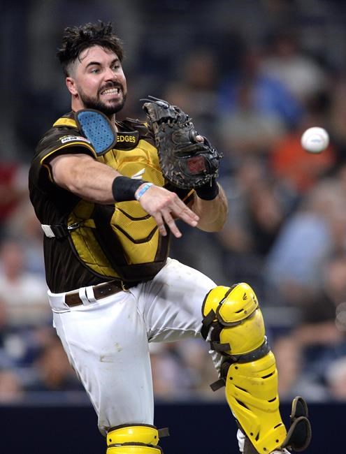 San Diego Padres catcher Austin Hedges throws to first base late on a wild pitch swinging strike-out by San Francisco Giants' Austin Slater during the sixth inning of a baseball game Friday, July 26, 2019, in San Diego. (AP Photo/Orlando Ramirez)