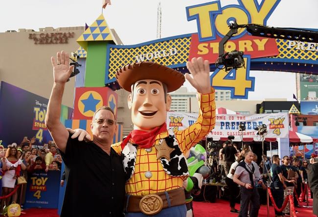 Tom Hanks, left, poses with his character Woody as he arrives at the world premiere of