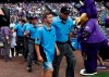 Thirteen-year-old Josh Cordova, left, of Denver, heads on the diamond with home plate umpire Cory Blaser before the Colorado Rockies host the Los Angeles Dodgers in the first inning of a baseball game Sunday, June 30, 2019, in Denver. The young man was officiating a youth baseball game when a brawl broke out among adults in the nearby suburb of Lakewood, Colo. (AP Photo/David Zalubowski)