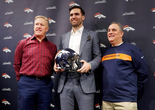 Denver Broncos quarterback Joe Flacco, center, holds his new team's helmet as general manager John Elway, left, and head coach Vic Fangio join in for a photograph during a news conference at the NFL football team's headquarters Friday, March 15, 2019, in Englewood, Colo. (AP Photo/David Zalubowski)