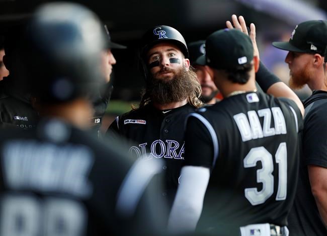 Colorado Rockies' Charlie Blackmon, center, is congratulated by teammates as he returns to the dugout after scoring on a single by Raimel Tapia off Arizona Diamondbacks starting pitcher Merrill Kelly in the first inning of a baseball game Monday, Aug. 12, 2019, in Denver. (AP Photo/David Zalubowski)